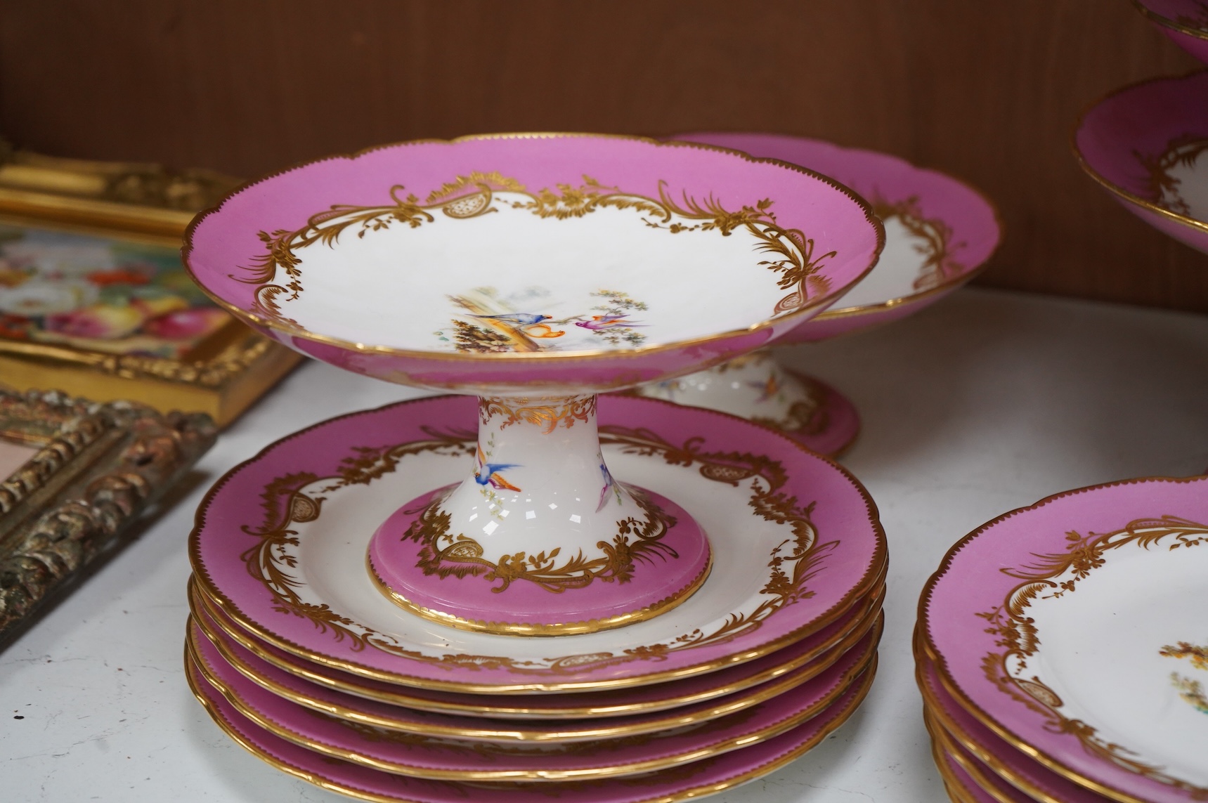 A Minton pink ground dessert service, in Sevres style, c.1850, hand painted with birds, comprising four comports and ten dessert plates, 23cm in diameter